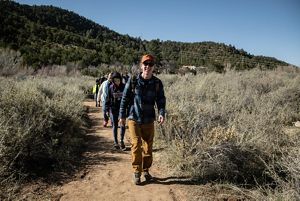 A group of people walk along a sandy trail.
