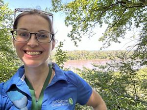 Sara Leavitt smiling on a trail near a river.