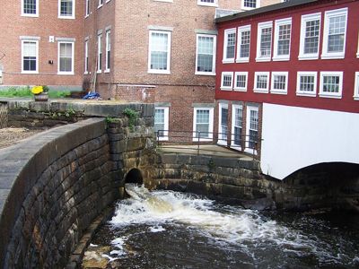 An old dam next to a historic brick building.