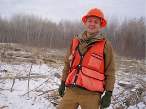 A smiling forester in an orange hard hat.