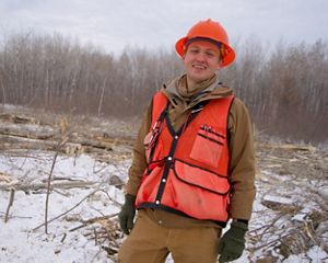 A smiling forester in an orange hard hat.