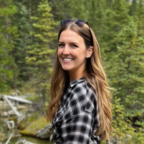 Person smiling in front of nature.