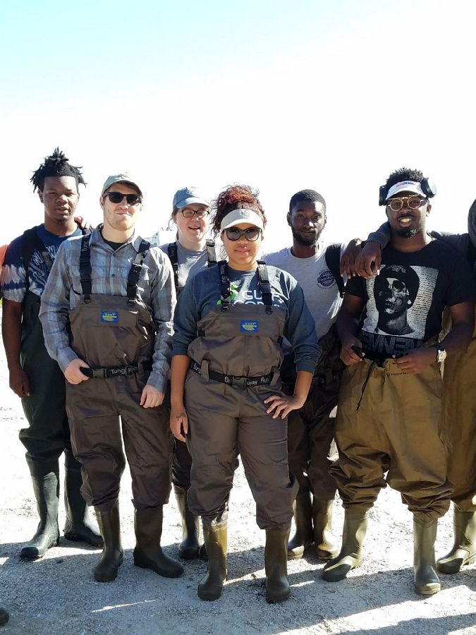 Six young people in waders smiling in the sun.