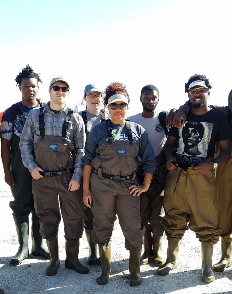Six young people in waders smiling in the sun.