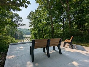 Two benches on a paved platform overlook a pond. 