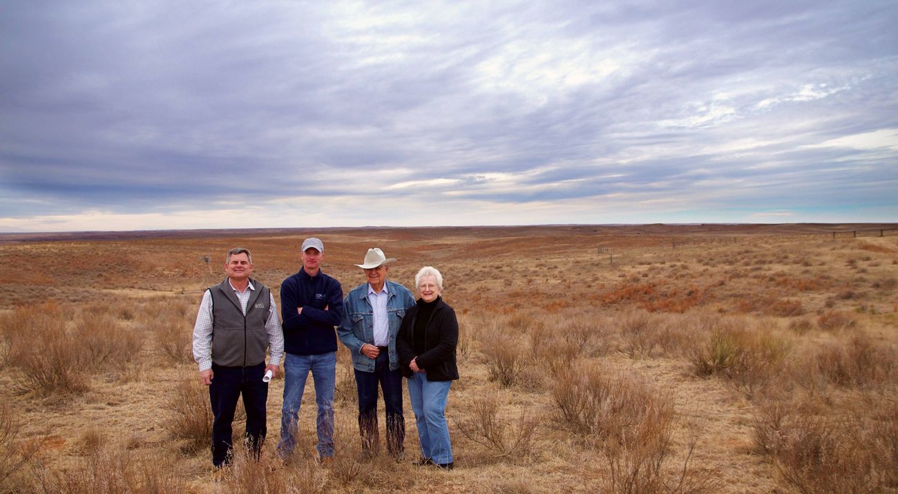 Four people standing in front of a cattle ranch in the Red Hills.