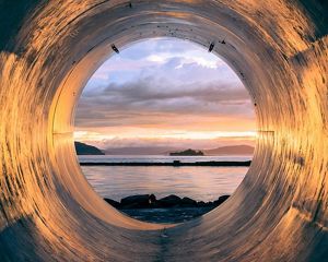 A large sewer pipe with an opening onto a beach.