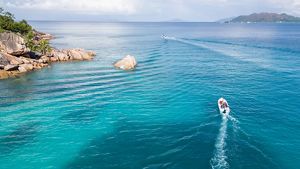 Un pequeño bote avanza a motor a través de las aguas turquesas de un afloramiento rocoso.