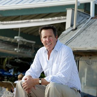 A smiling man sitting in front of a seafood restaurant.