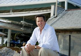 A man sitting in front of a restaurant, smiling.