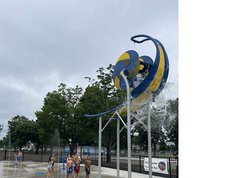 Children playing on a splash pad with water all around.