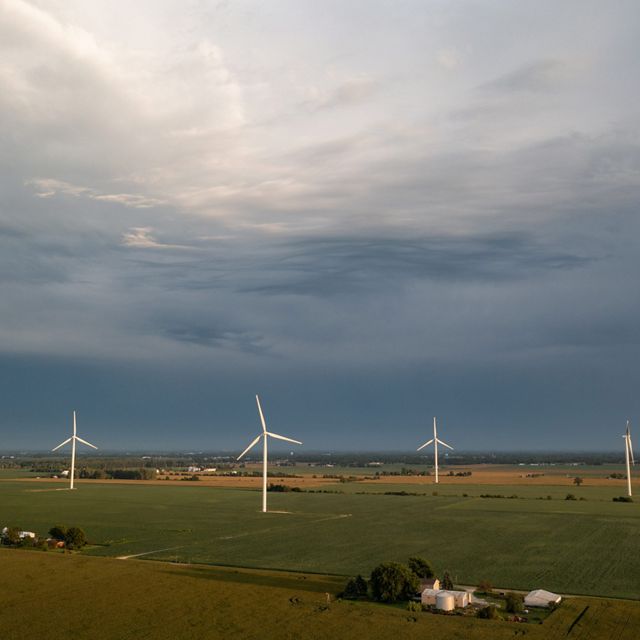 Wind turbines on farmfield against darkening skies.