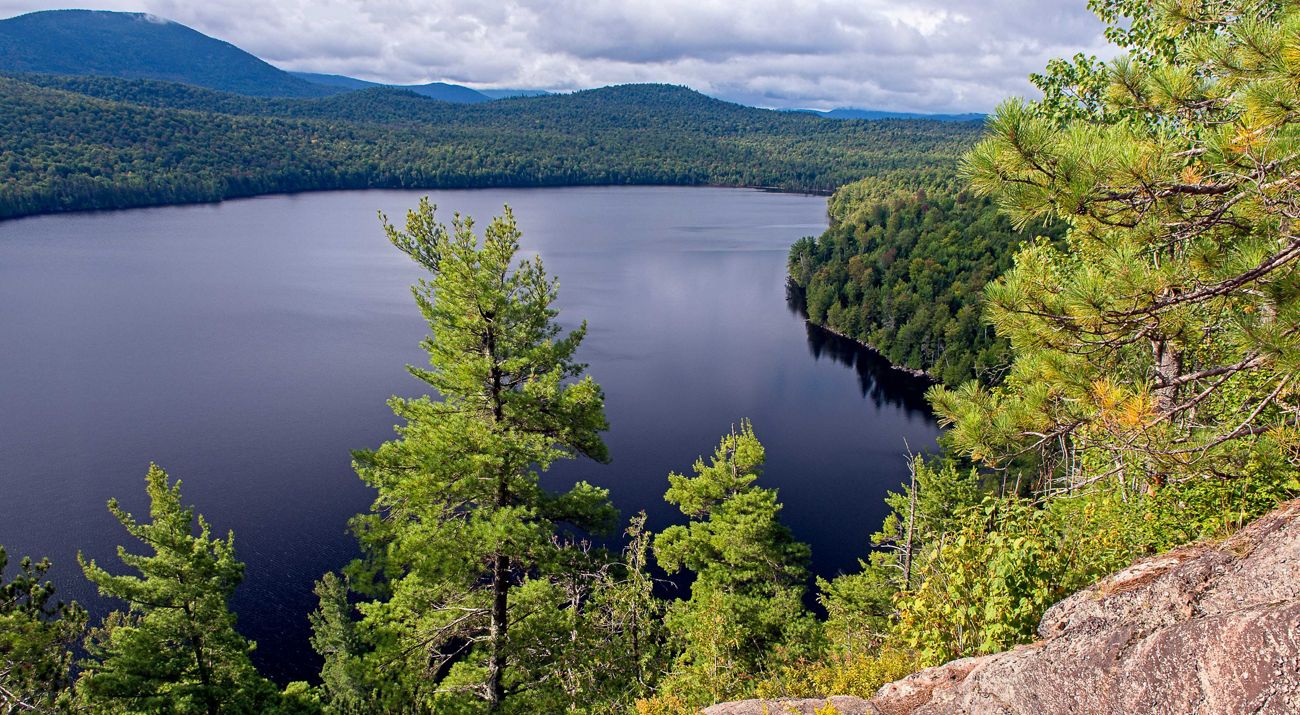 A lake surrounded with dark green forests.