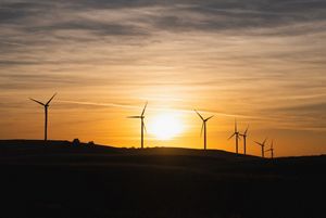 Wind turbines spin in front of a sunset in Montenegro.