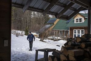 Cain in the winter with smoke coming out, snow on the ground, and wooden logs in the front. 