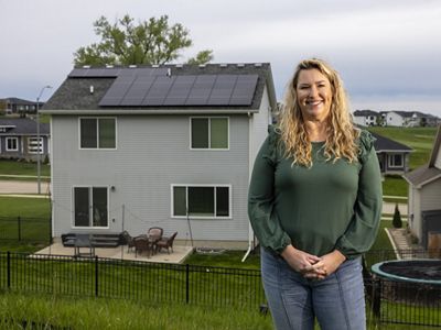 Jessica Maldonado stands in front of her home that has solar panels on the roof.