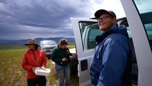 Three crew members, including Colton Folts, stand next to pickup trucks in the sage in Montana.