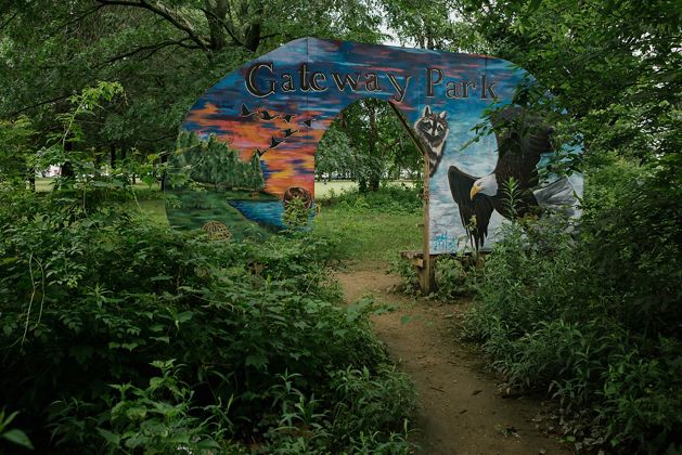 A plywood gateway featuring painted wildlife frames the entrance to Gateway Park
