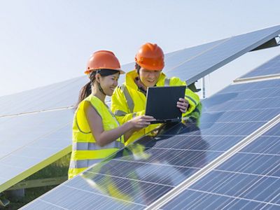 One male and one female engineer using notebook computer and discussing at the solar panel.
