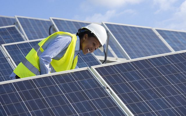 A worker tends to solar panels and inspects them.