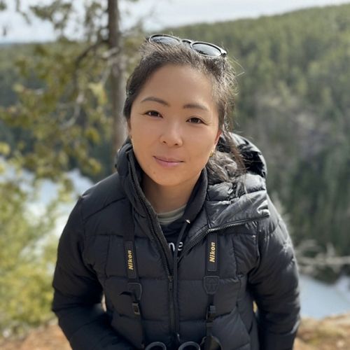 Person in jacket in front of mountains.