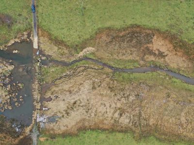 An aerial view of a bog with a stream flowing from left to right.