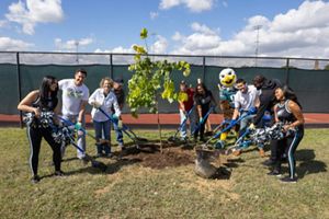 Philadelphia Eagles mascot, cheerleaders and representatives shovel dirt atop the base of a newly-planted tree.