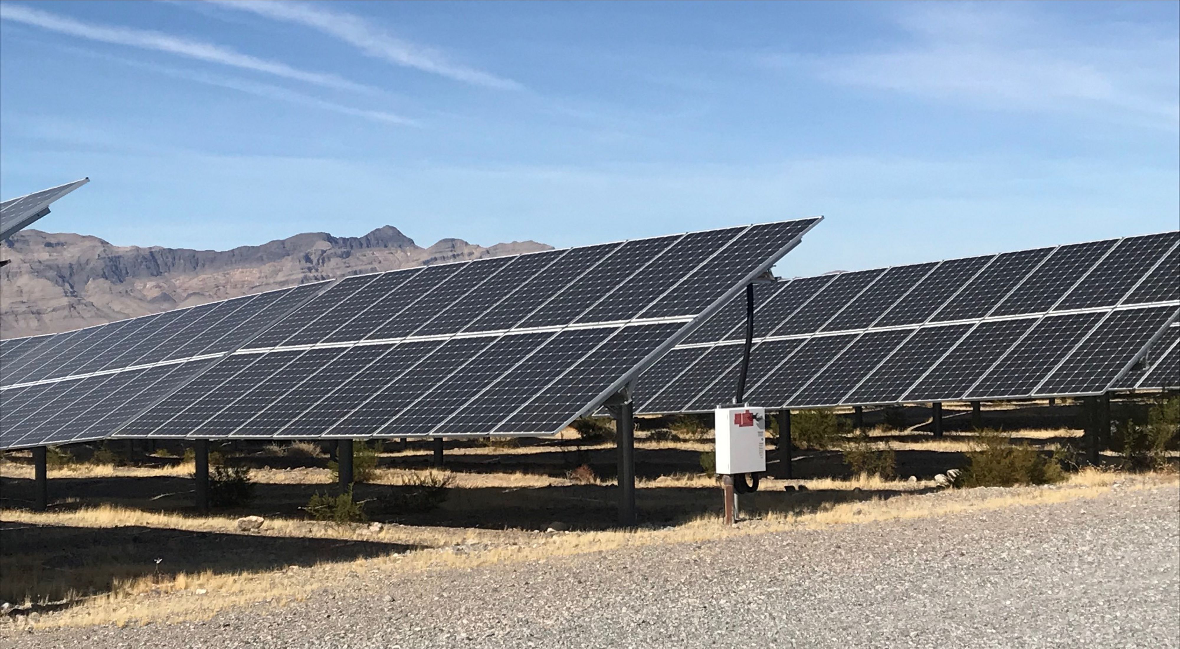 Photo of solar panels in the Nevada desert, mountains in distance.