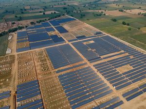 An aerial image of a massive solar farm featuring grids of solar panels in a field.