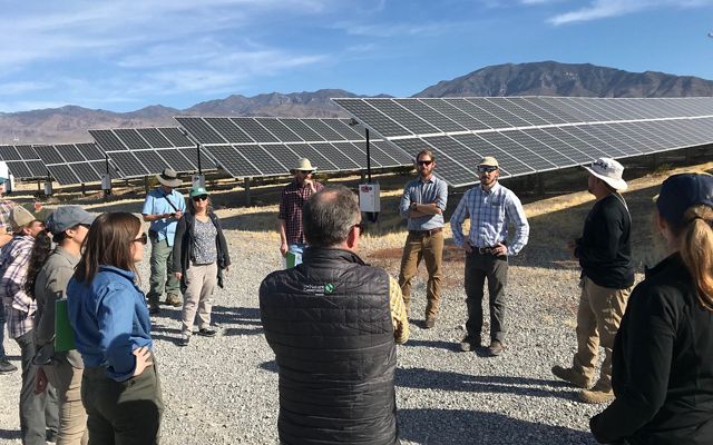 Group of people in discussion beside a Nevada solar array.