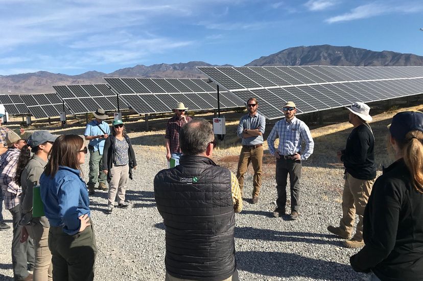 Group of people in discussion beside a Nevada solar array.
