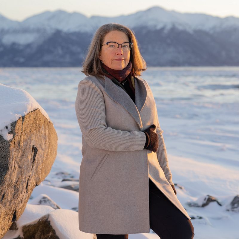 a woman posing for a photo in a snow-covered landscape.