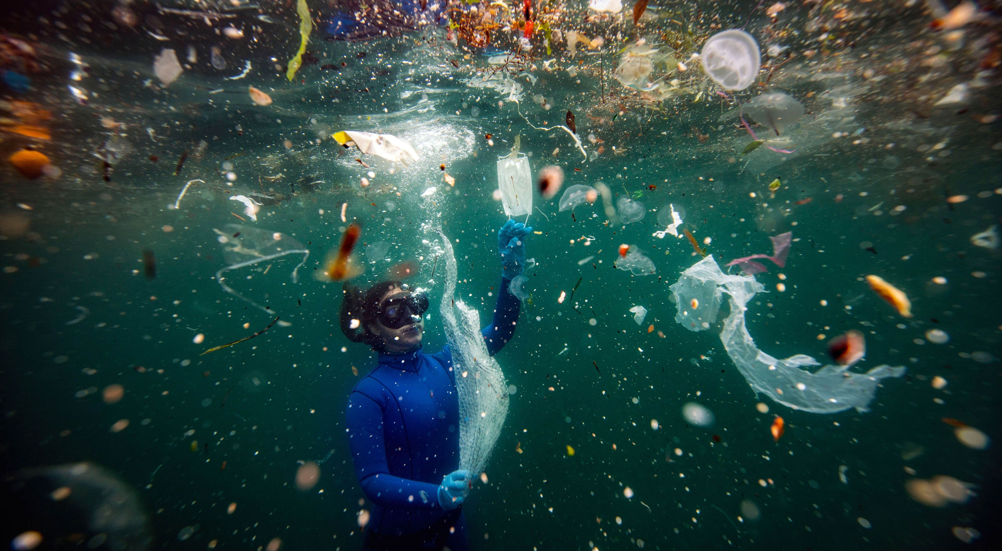 A diver swims among trash—including plastic bottles and medical masks—in the Bosporus Strait in Turkey.