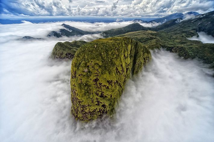 Una vista aérea de una cordillera que emerge por encima de densas nubes.