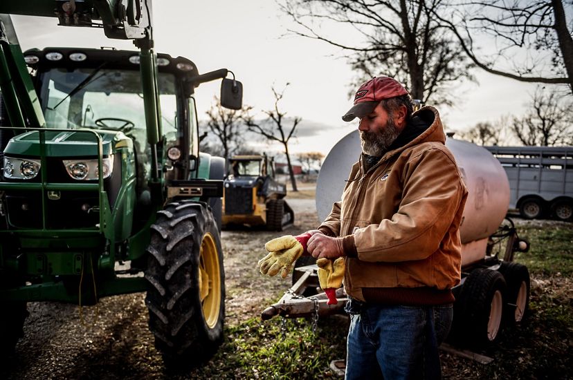 Ross Wahl puts on work gloves in front of a tractor at SAVE Farm.