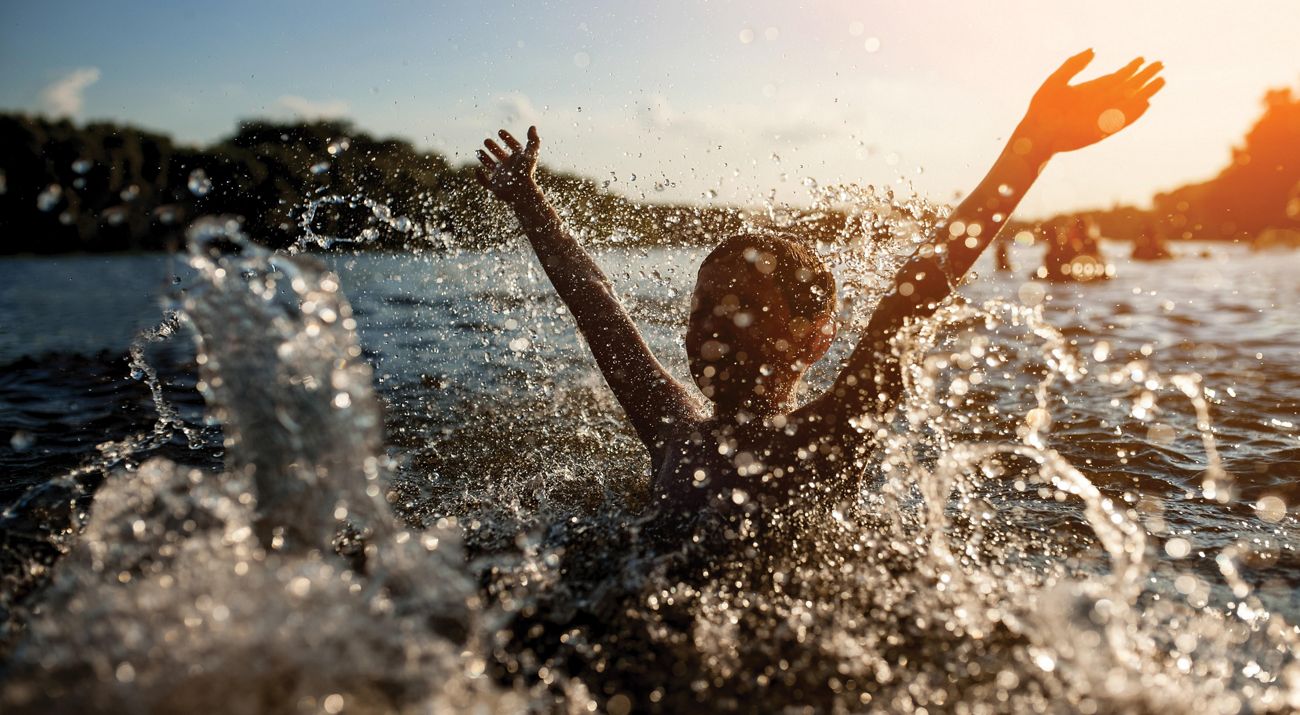 A child splashing in the water of a lake.