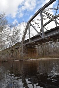 A river flows under a steel bridge. 
