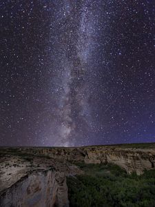 The Milky Way and stars in view over a purple-hued night sky at Little Jerusalem Badlands State Park. 