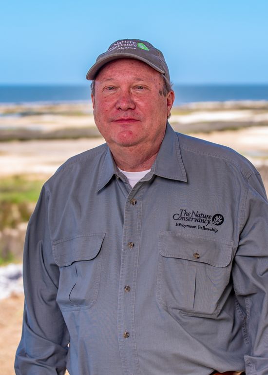 A headshot of Steve Nortcutt standing in front of a sandy shoreline.