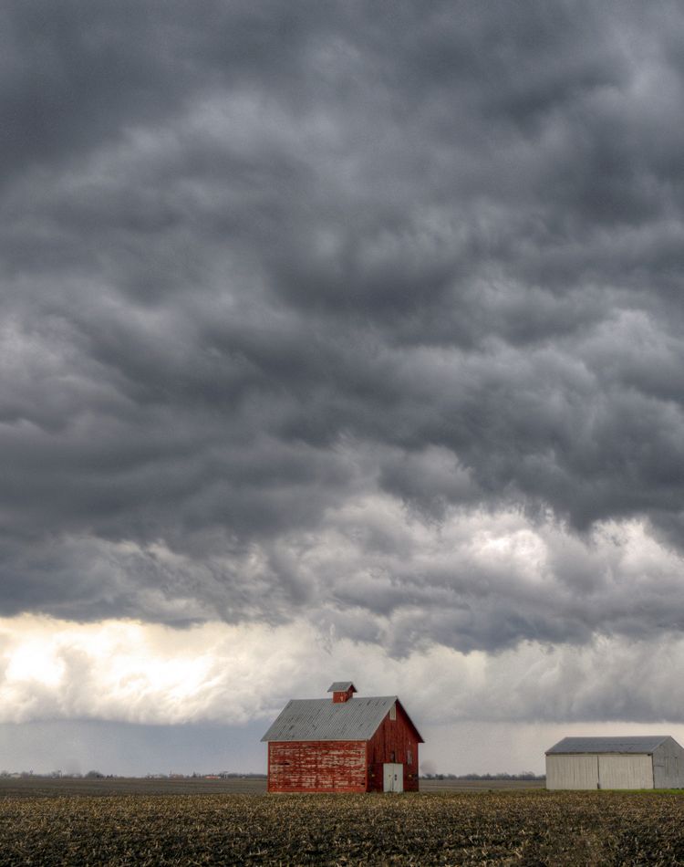 Storm clouds gather above a farm field.