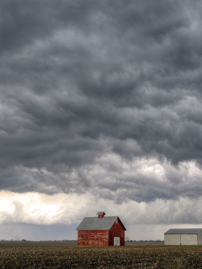 Storm clouds gather above a farm field. 
