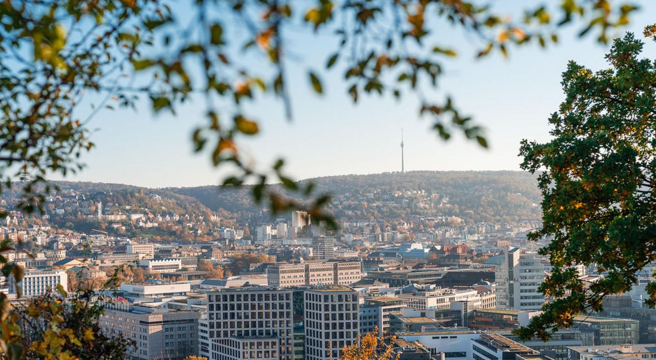 Vista panorámica de Stuttgart con edificios bordeada de colinas y vegetación.