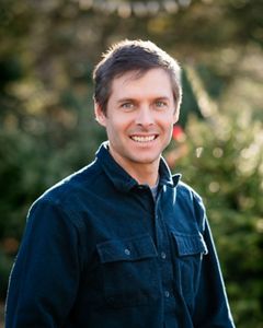 Headshot of Steve Kirk, coastal program director, in front of a blurred leafy green background.