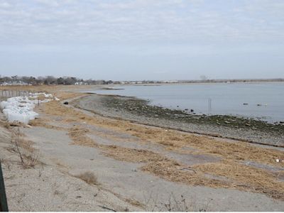 A rocky, barren shore area with a large body of water to the right.