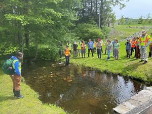 A group of people gather around a narrow stream. 