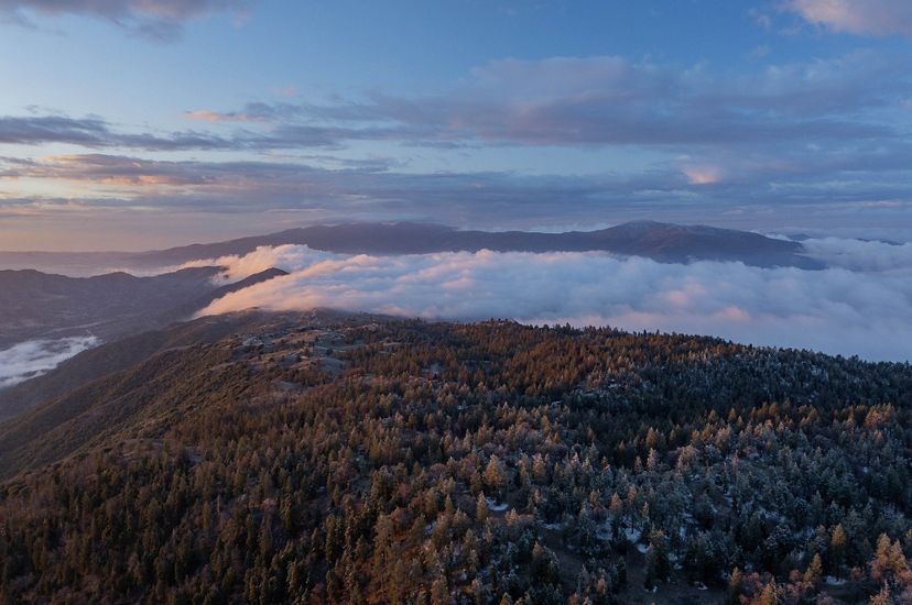 Clouds pour over the snow-covered Bear Mountain as the sun rises in Tehachapi, California.