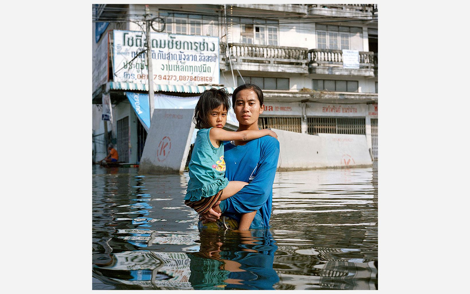 Anchalee Koyama holds her daughter over deep floodwater in the Taweewattana district of Bangkok, Thailand