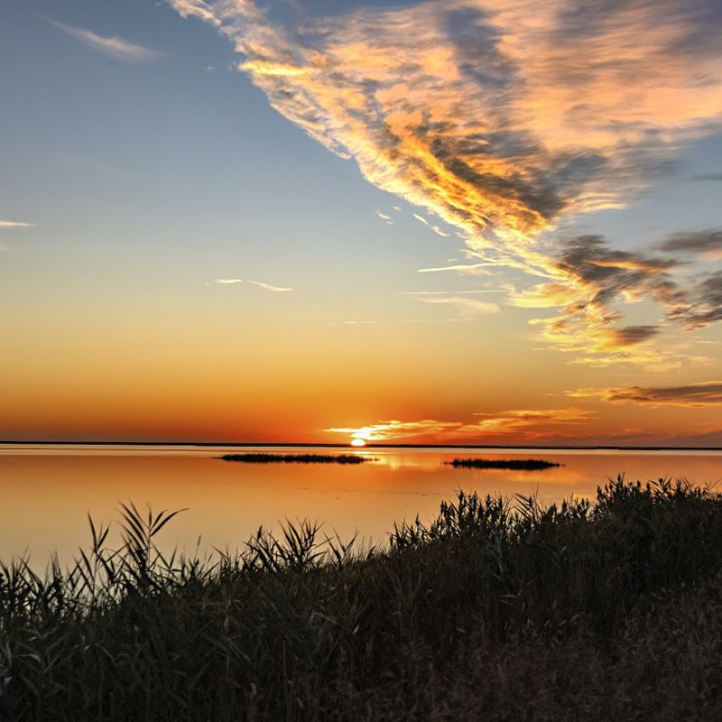 The sun sets over the Delaware Bay creating an orange reflection in the water.