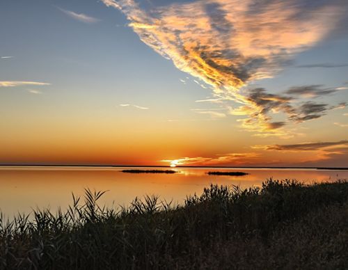 The sun sets over the Delaware Bay creating an orange reflection in the water.
