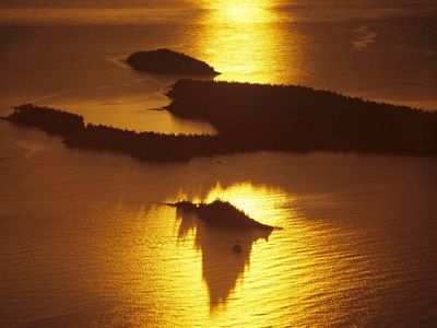 Aerial view of the sun setting over an island.